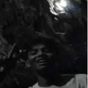 Person on a nocturnal nature walk, holding a flashlight and surrounded by the starry night sky and silhouetted trees